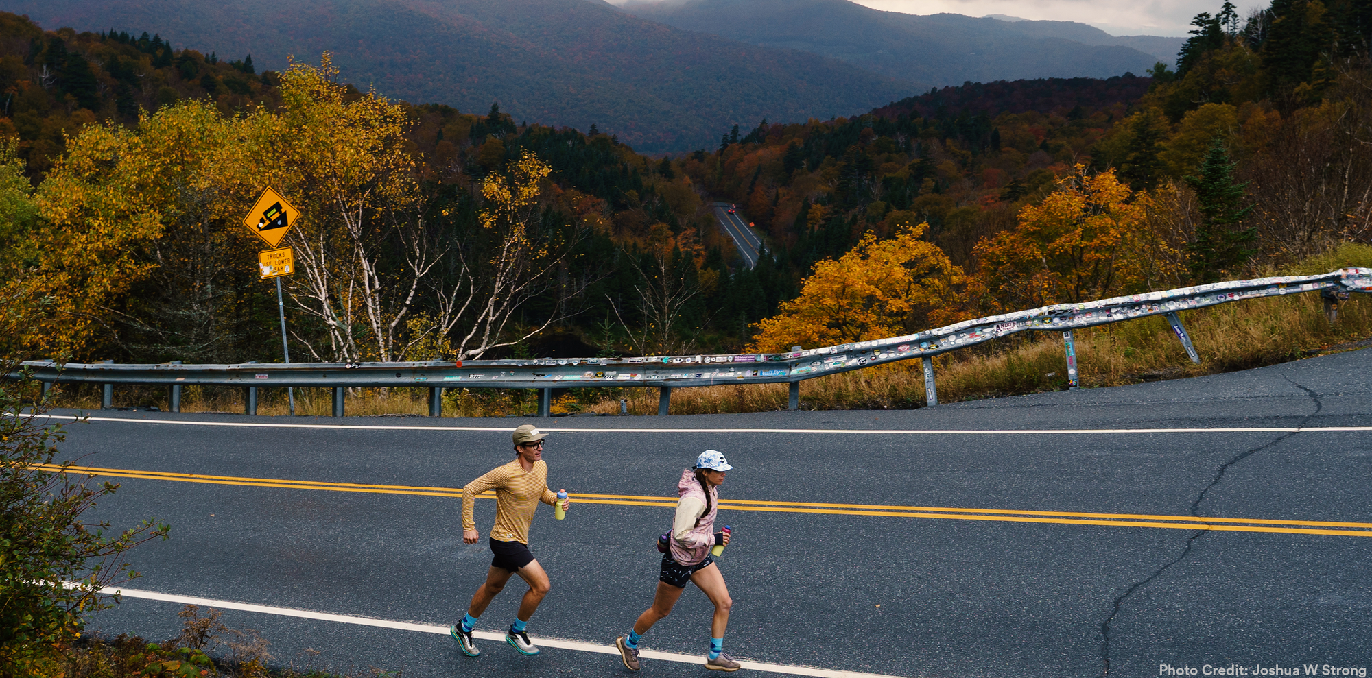 Two people running up a hill holding stainless steel water bottles