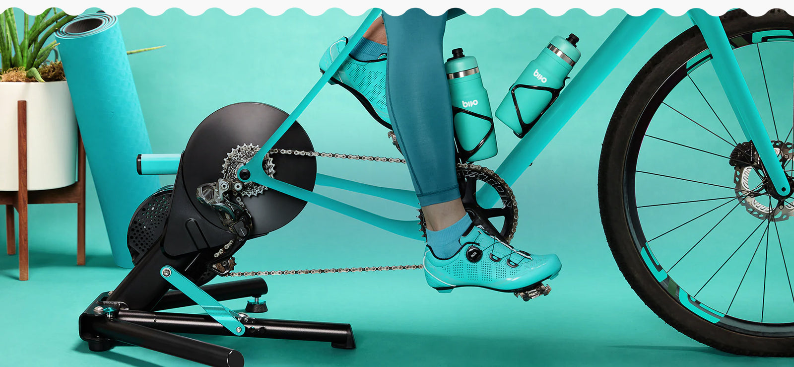Person on a stationary bike against a teal background with 2 teal Bivos in the bike cage