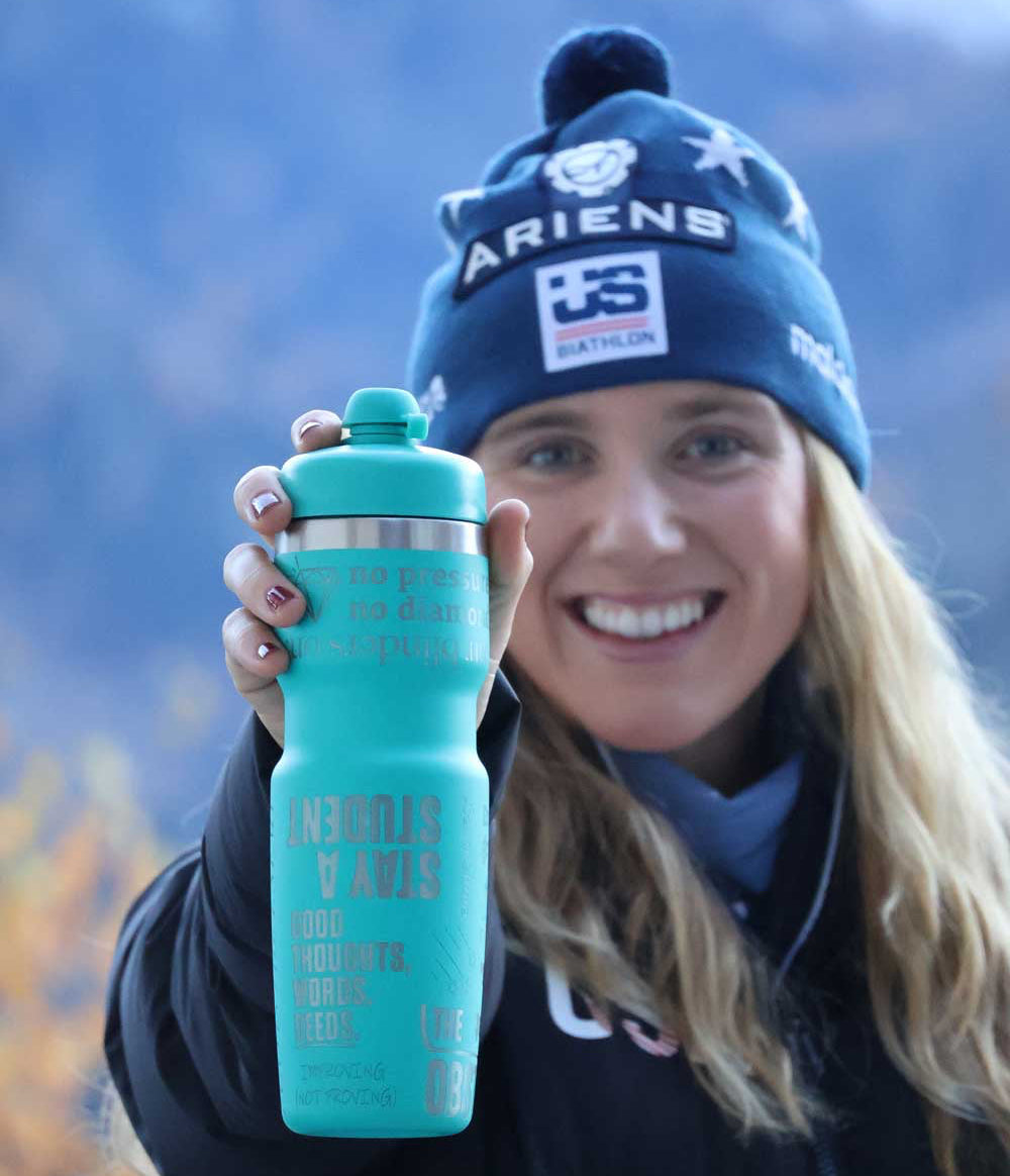 Person wearing a blue beanie with visible branding, holding a teal water bottle outdoors.