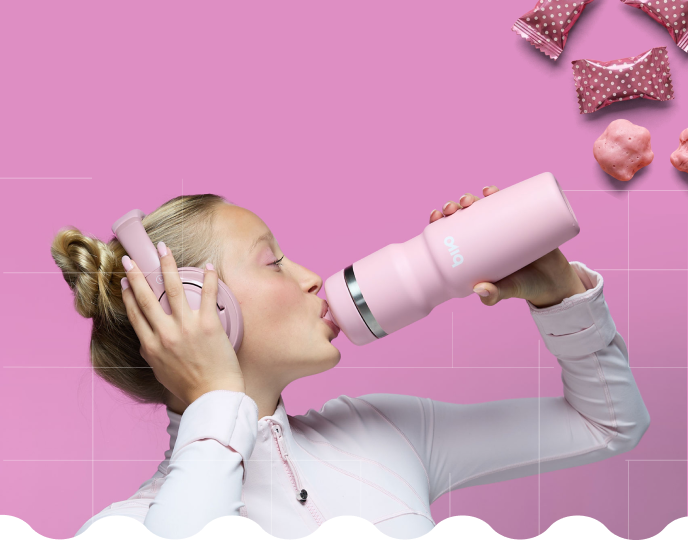 Girl Drinking from Bivo Bubblegum colored bottle on a pink background with pink nails wearing pink over-ear headphones.