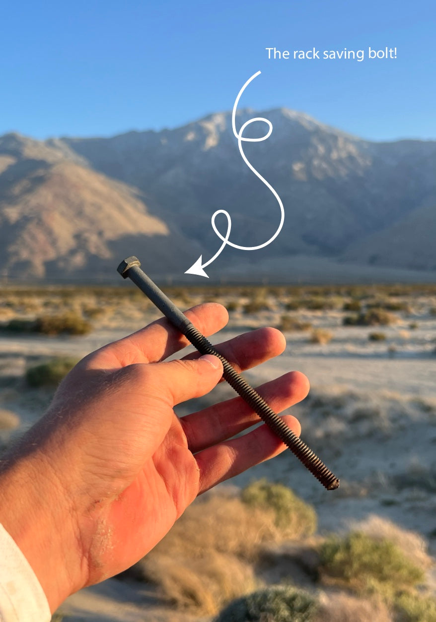 Hand holding a bolt with a desert landscape and mountains in the background