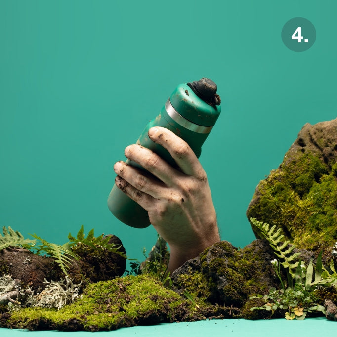 Hand holding a green water bottle with a textured surface against a teal background