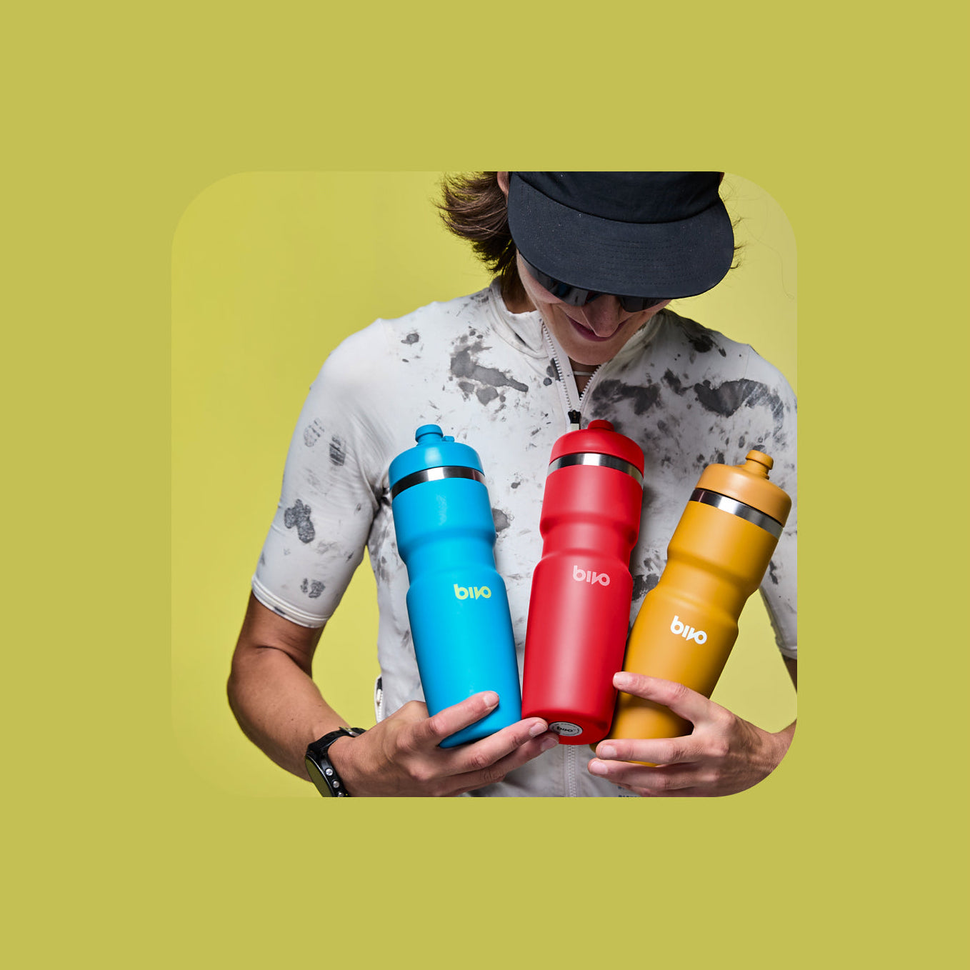 Person holding three colorful Bivo water bottles with 'bivo' branding on a yellow background